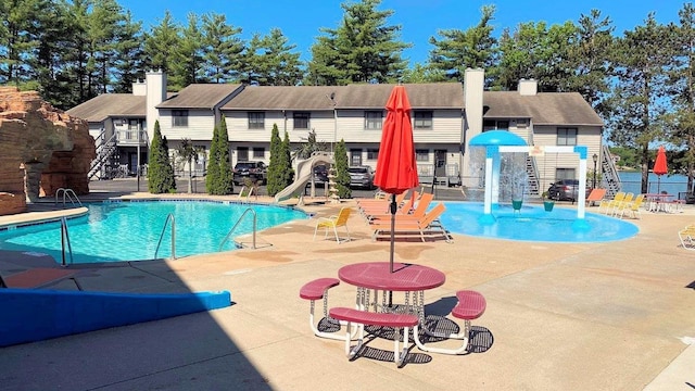 community pool featuring fence, a water slide, and a patio