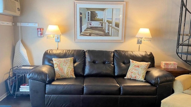 living area featuring baseboards, wood finished floors, and a wall mounted air conditioner