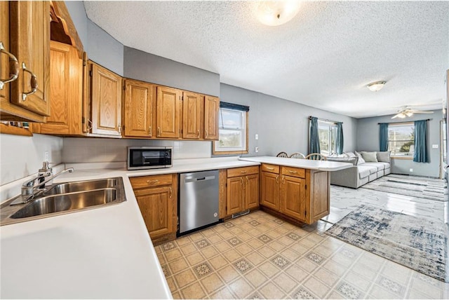 kitchen with appliances with stainless steel finishes, light countertops, a sink, and a peninsula