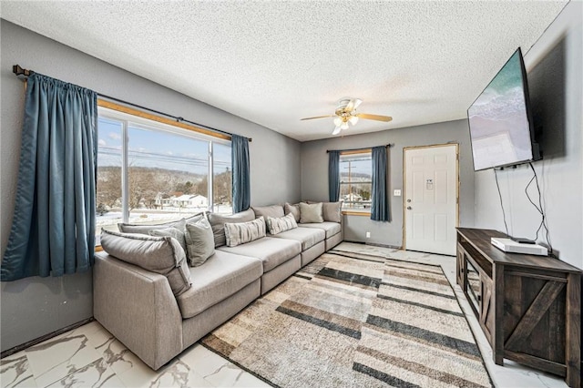 living area featuring a textured ceiling, marble finish floor, and ceiling fan