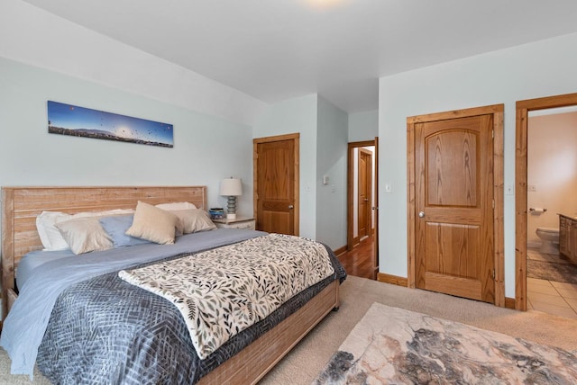 bedroom featuring baseboards, ensuite bath, and light colored carpet