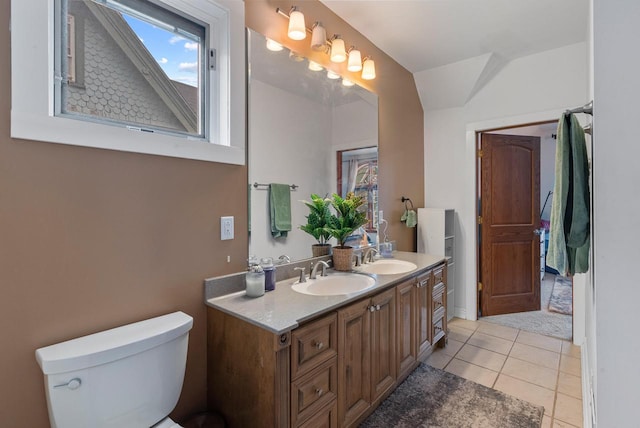 bathroom with double vanity, tile patterned flooring, a sink, and toilet