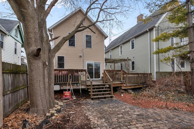 rear view of property featuring fence and a wooden deck