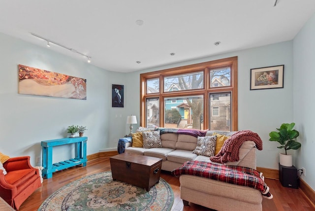 living room featuring rail lighting, baseboards, and wood finished floors