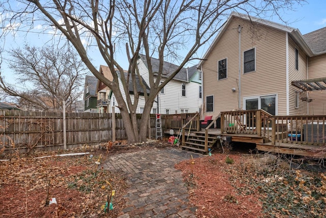 rear view of property featuring a patio area, fence, and a deck