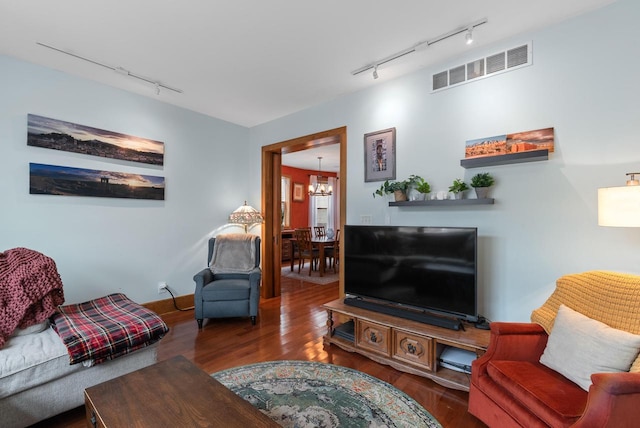 living room featuring rail lighting, wood finished floors, visible vents, and a notable chandelier