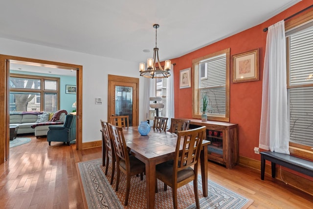 dining space with light wood-style floors, a notable chandelier, and baseboards