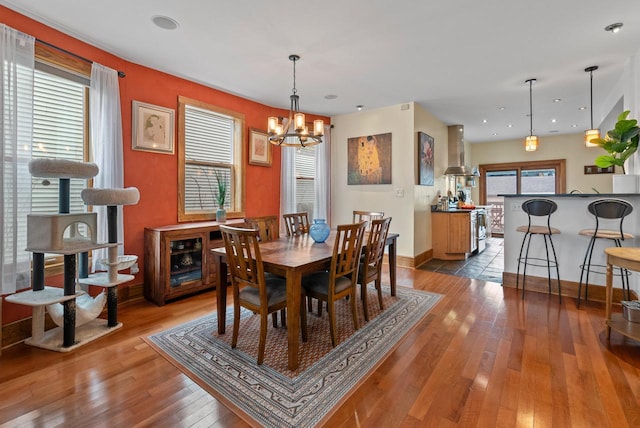 dining area with a chandelier, hardwood / wood-style flooring, and baseboards