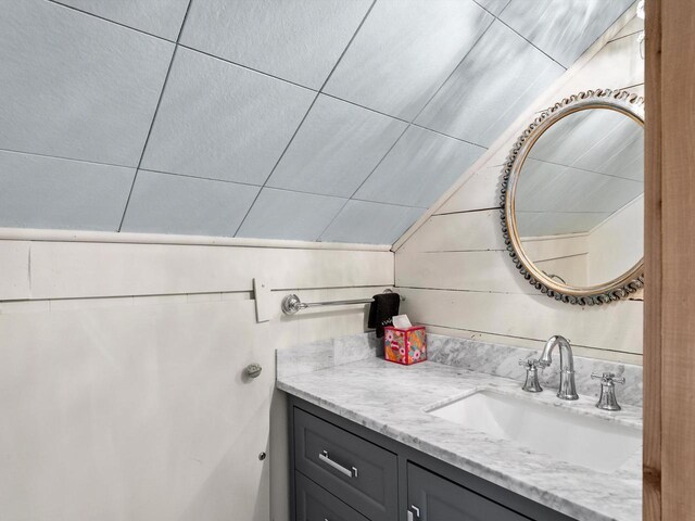 bathroom with wooden walls, vaulted ceiling, and vanity