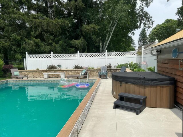 view of swimming pool featuring a fenced backyard and a hot tub