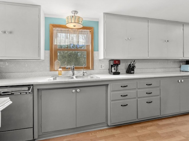 kitchen featuring a sink, light countertops, dishwasher, and gray cabinetry