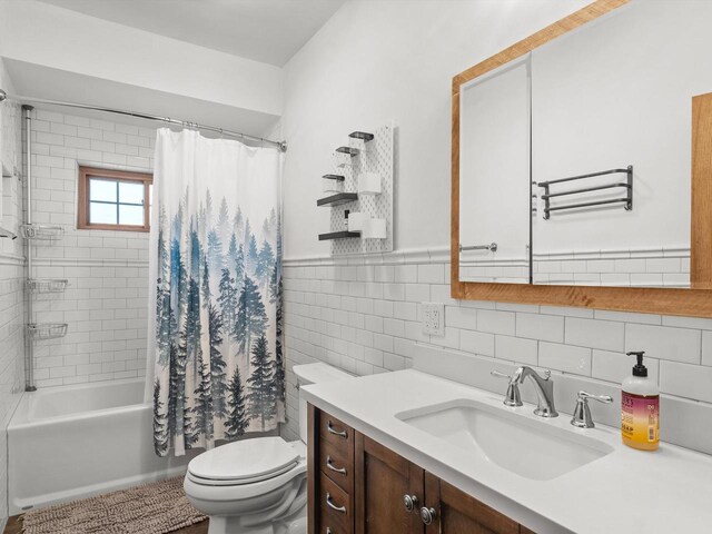 bathroom with toilet, a wainscoted wall, shower / bath combo with shower curtain, vanity, and tile walls