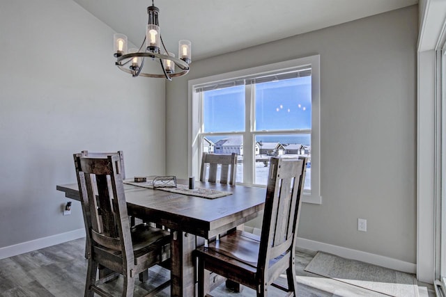 dining room with baseboards, a notable chandelier, and wood finished floors