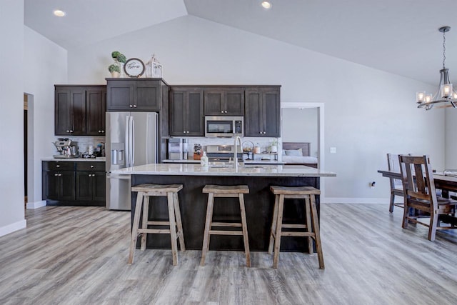 kitchen with a chandelier, stainless steel appliances, dark brown cabinets, and a breakfast bar area