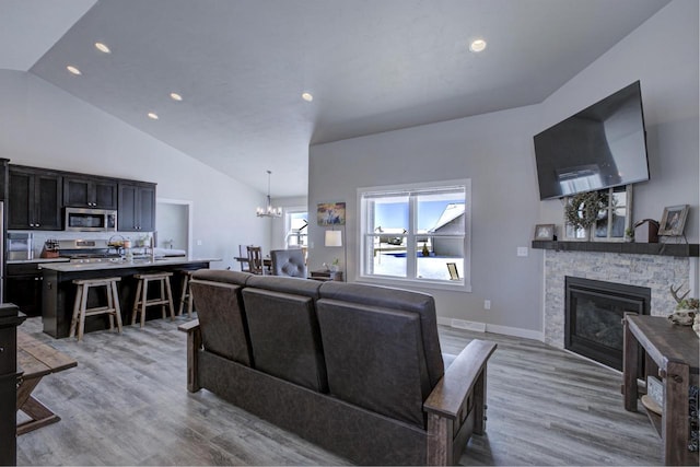 living area featuring a chandelier, recessed lighting, light wood-style flooring, and a stone fireplace