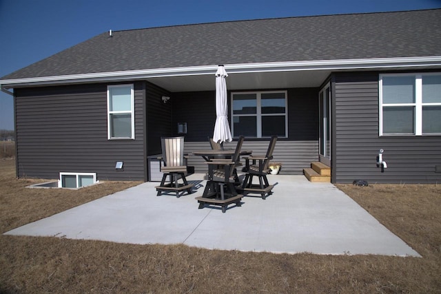 rear view of house featuring a shingled roof and a patio area