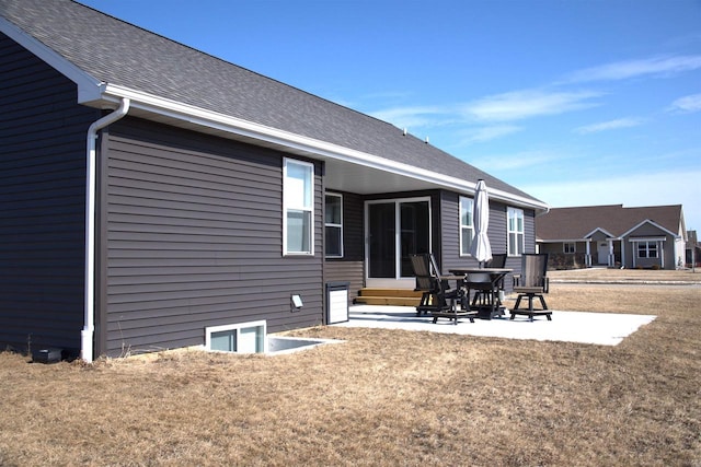 back of property featuring roof with shingles, a lawn, and a patio