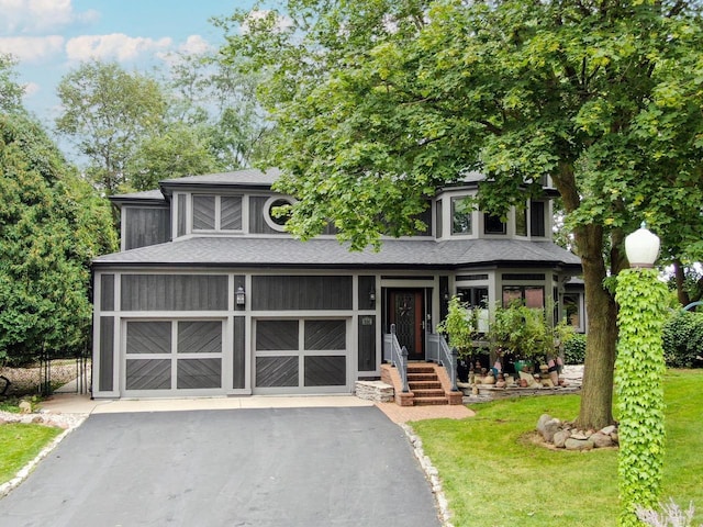 view of front facade with aphalt driveway, a front lawn, a shingled roof, and a garage