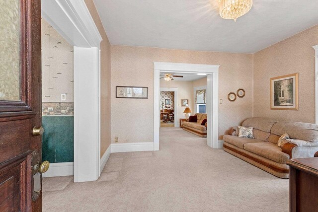 living area featuring light carpet, wallpapered walls, and baseboards