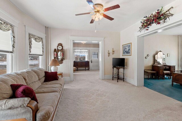 living room with light carpet, ceiling fan, and baseboards