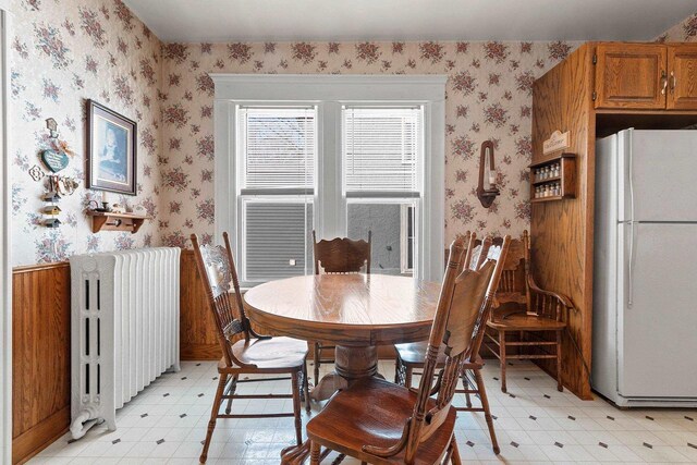 dining room featuring light floors, radiator heating unit, and wallpapered walls