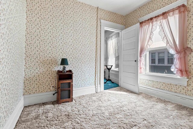 unfurnished bedroom with multiple windows, carpet flooring, and wallpapered walls