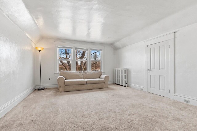 sitting room featuring carpet, radiator, vaulted ceiling, and baseboards