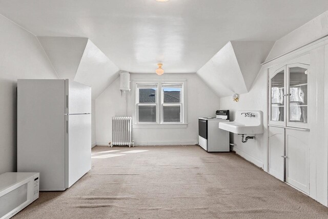 bonus room with lofted ceiling, washer / clothes dryer, radiator, light colored carpet, and a sink