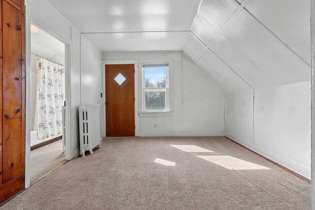 additional living space with vaulted ceiling, radiator heating unit, and carpet flooring