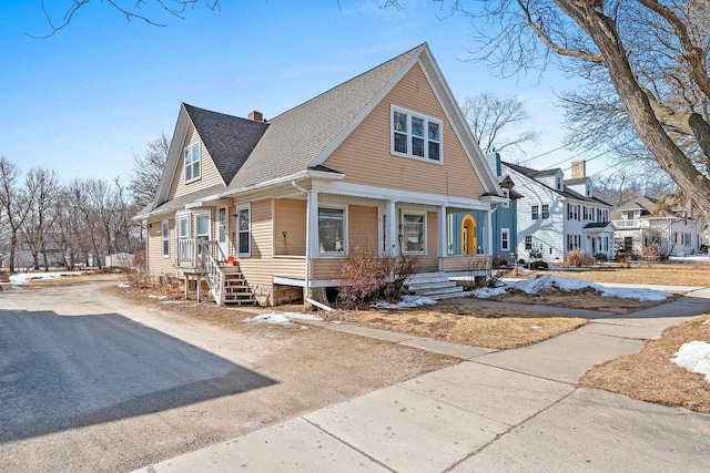 view of front of property featuring a shingled roof, a residential view, covered porch, and a chimney