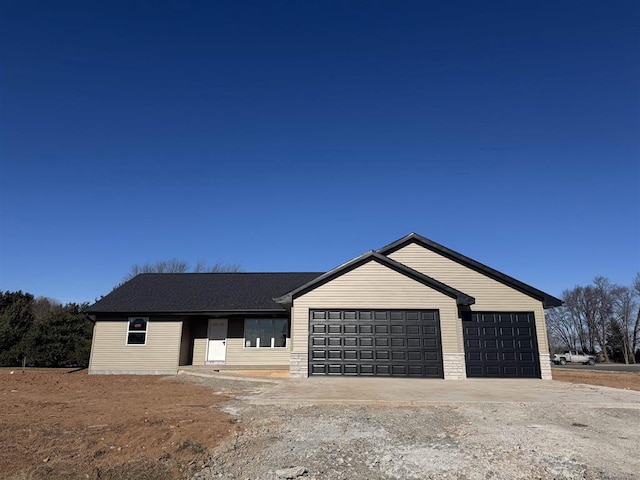 view of front of home with a garage, stone siding, and driveway