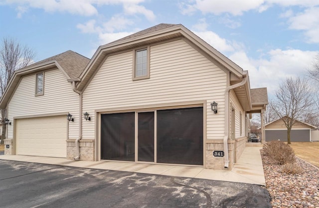 exterior space with a shingled roof, brick siding, and a garage