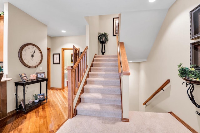 staircase featuring baseboards, wood finished floors, and recessed lighting