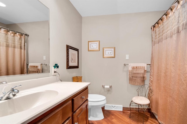 full bath with baseboards, visible vents, toilet, wood finished floors, and vanity