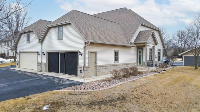 view of property exterior featuring a garage, roof with shingles, a yard, and aphalt driveway