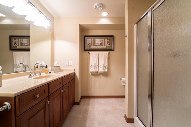 bathroom with a shower stall, baseboards, and vanity