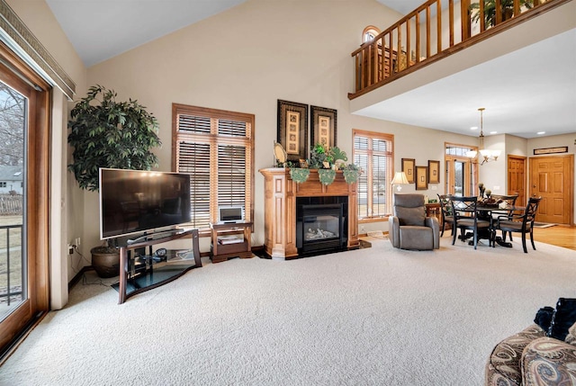 carpeted living room featuring a fireplace with flush hearth, recessed lighting, a chandelier, and high vaulted ceiling