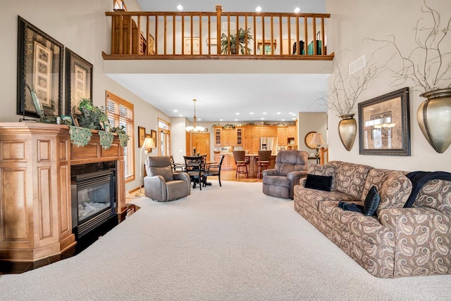 carpeted living area featuring a high ceiling, a glass covered fireplace, and recessed lighting