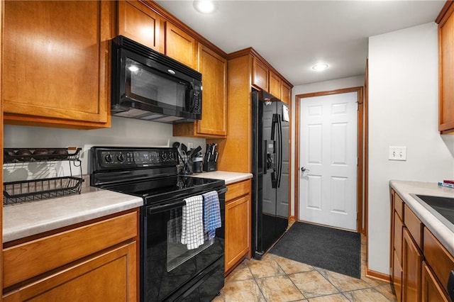 kitchen featuring brown cabinets, recessed lighting, light countertops, black appliances, and baseboards