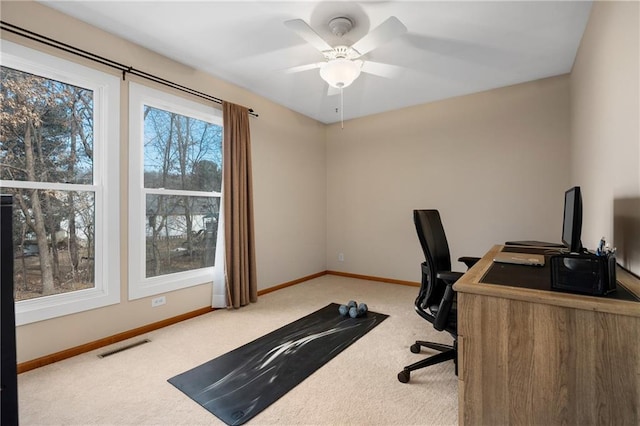 carpeted office space featuring ceiling fan, visible vents, and baseboards