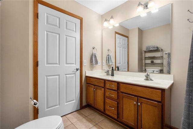 bathroom with double vanity, tile patterned flooring, toilet, and a sink