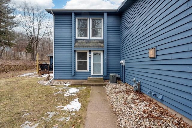 entrance to property featuring central AC, a yard, and fence