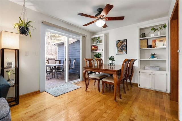 dining room with light wood finished floors, ceiling fan, built in shelves, and baseboards