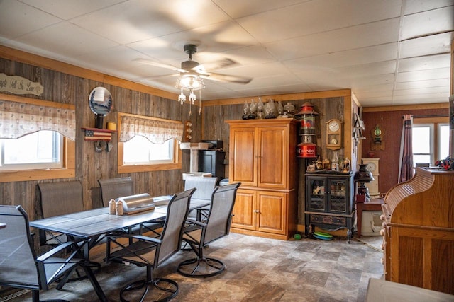 dining space with a ceiling fan and wooden walls