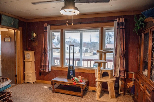 sitting room featuring a wealth of natural light, visible vents, wooden walls, and carpet