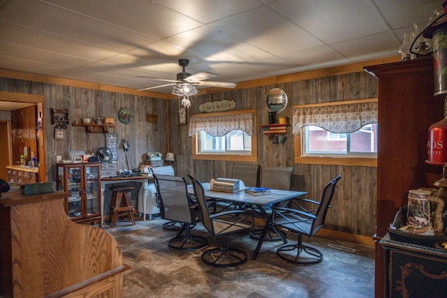 dining space featuring a ceiling fan and wooden walls