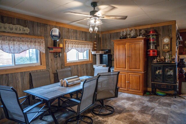 dining room featuring ceiling fan and wooden walls