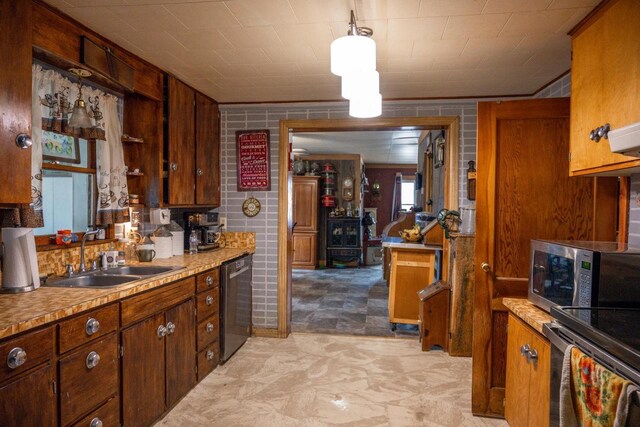 kitchen with brown cabinetry, appliances with stainless steel finishes, light countertops, and a sink