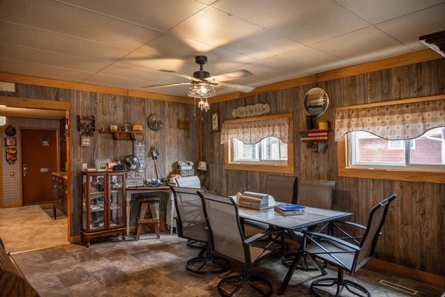 dining area featuring ceiling fan, wood walls, and visible vents