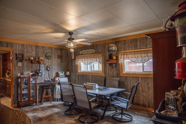 dining room with wooden walls, visible vents, and a ceiling fan